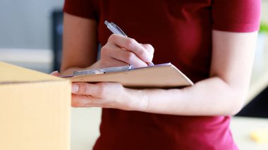 Kurye, teslimat kağıdını imzalayan Asyalı bayan dükkan sahibine posta paketi teslim ediyor. Kapıdan kapıya nakliye, E-ticaret sektörü konsepti