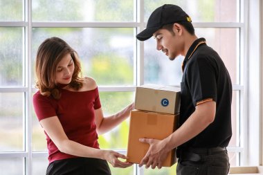 Güzel Asyalı bayan müşteri, yakışıklı Asyalı kuryeden aldığı paketleri sayıyor. Kapıdan kapıya nakliye, e-ticaret konsepti.