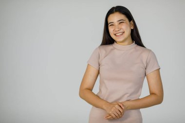 Genç ve sevimli siyah düz saçlı, gülümseyen yüzlü Asyalı kadın pozu..