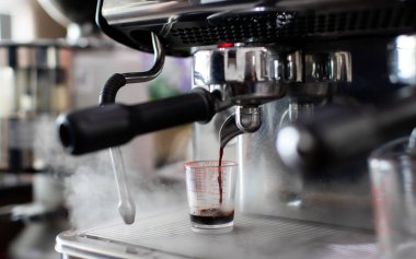 Kahve makinesiyle kafeteryada kahve yaparken çekilmiş bir fotoğraf. Profesyonel modern espresso kahve makinesi bardağa sıcak içecek doldurur. Kahveyi kafeye koy.