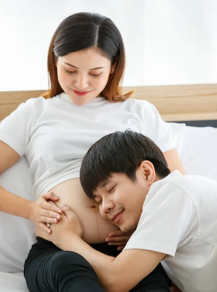 一个即将成为父亲的非常快乐的亚洲男人的画像 他坐在那里 听着一个胎儿在他怀孕的妻子的肚子里带着爱和快乐的声音 — 图库照片