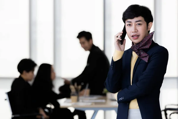 LGBTQ transseksüel ofis çalışanının portresi. Sıradan takım elbiseli. Akıllı telefonda zarif bir şekilde konuşuyor.