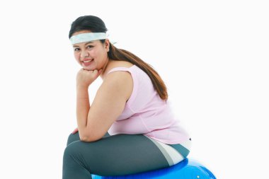 Asyalı, mutlu, sağlıklı, spor elbiseli, saç bandı takmış, mavi spor spor salonuna gülümseyen, beyaz arka planda çenesi olan şişman bir kızın portresi..