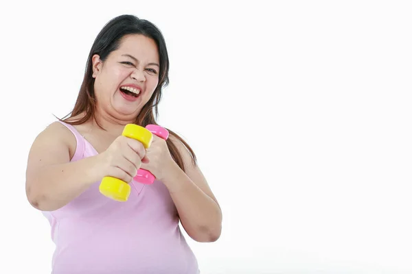 亚洲快乐健康强壮的胖妞笑着抬起粉色和黄色哑铃 两只胳膊在前面白色的背景下练习减肥 — 图库照片