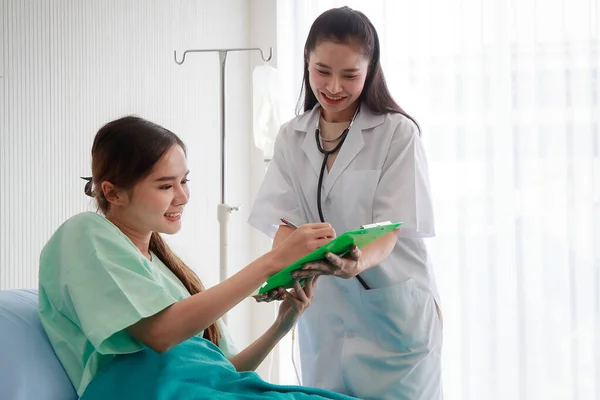 Nice asian female doctor using stethoscope to check on her young patient woman heartbeat and lung in the hospital. Health care and medical concept