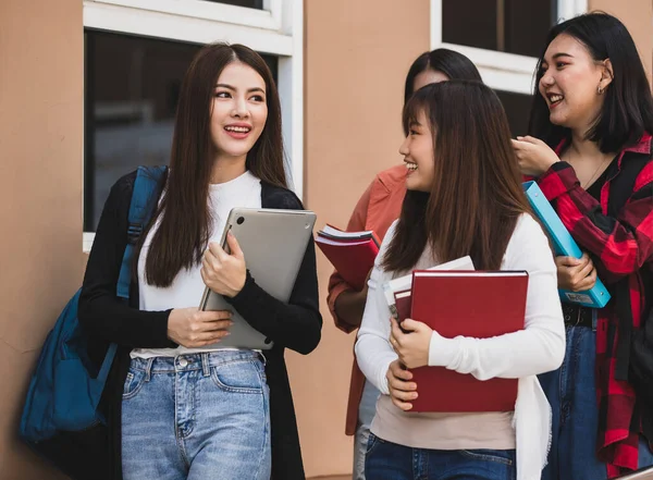 Group of four young attractive asian girls college students standing together talking in university campus. Concept for education and college students life.