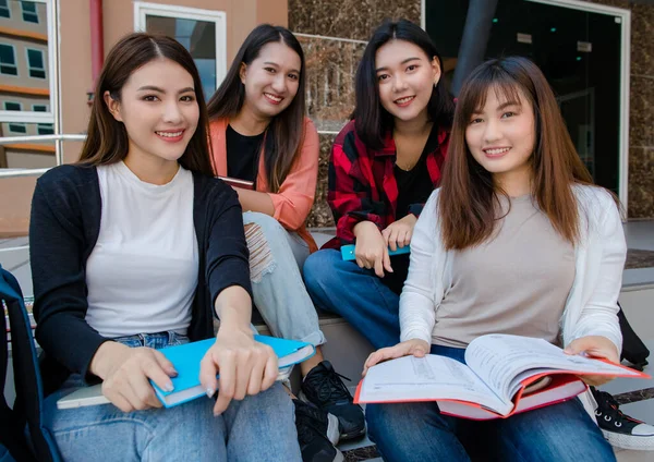 Group of four young attractive asian girls college students studying together in university campus outdoor looking at camera. Concept for education, friendship and college students life.