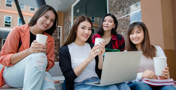 Group of four young attractive asian girls college students studying together in university campus outdoor looking at camera. Concept for education, friendship and college students life.