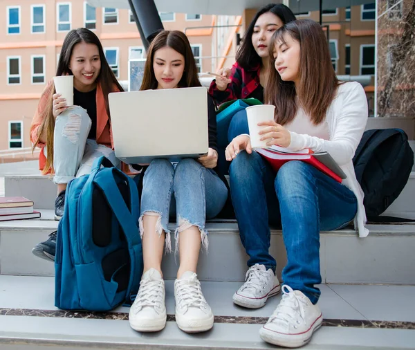 Group of four young attractive asian girls college students studying together using laptop in university campus outdoor. Concept for education, friendship and college students life.