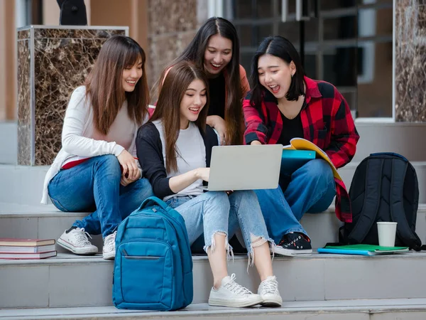 Group of four young attractive asian girls college students studying together using laptop in university campus outdoor. Concept for education, friendship and college students life.