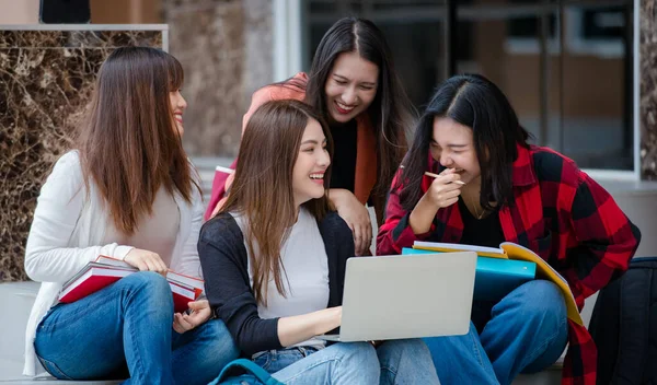 Group of four young attractive asian girls college students studying together using laptop in university campus outdoor. Concept for education, friendship and college students life.