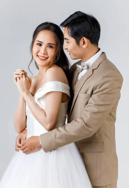 若い魅力的なアジアのカップル 男性はベージュのスーツを着て 女性は白いウェディングドレスを着て 男は後ろから女性を抱きしめる 結婚式前の写真のコンセプト — ストック写真