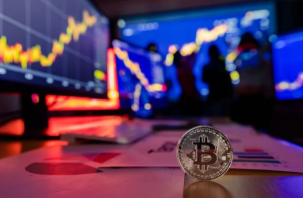 Altın bitcoin kripto döviz jetonu masanın üstünde, mali analiz grafiği grafiğinde bilgisayar ve dizüstü bilgisayar ekranında büyüme raporunu takas ederken simsar arka planda bulanık bir şekilde buluşuyor..