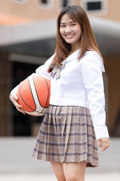 女子大生 女子大生でハンドバスケットボールをスマートでハッピーなポーズで開催している若いアジア人女子大生のポートレート 制服姿の10代 — ストック写真