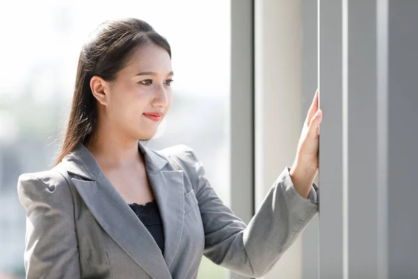 Asiatiska Leende Kvinna Grå Kostym Står Kontorsfönstret Begreppet Självsäker Arbetande — Stockfoto