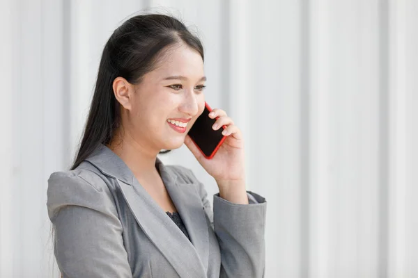 亚洲微笑的女人手持智能手机 女商人在办公室通过电话谈论工作 美丽自信的职业女性 — 图库照片