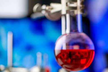 Patojenik mikroorganizmayı veya virüsü teşhis etmek için bilimsel deney amacıyla kimyasal cam şişenin içindeki kırmızı reaksiyonlu çözeltiye bilgisayar ekranından yansıyan mikrop..