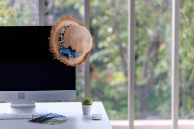 Yaz tatili reklamları için siyah boş bilgisayar monitörü ekranı ve geniş kenarlı hindistan cevizi suyu ile ön bahçedeki bulanık bahçe arka planında saman klavye fare ağacı kabı ile kopyalama alanı.