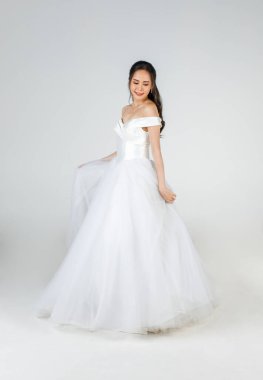 Genç ve çekici bir Asyalı kadın, yakında gelin olacak, beyaz gelinlik giyiyor ve mutlu görünüyor. Düğün öncesi fotoğrafçılık kavramı.