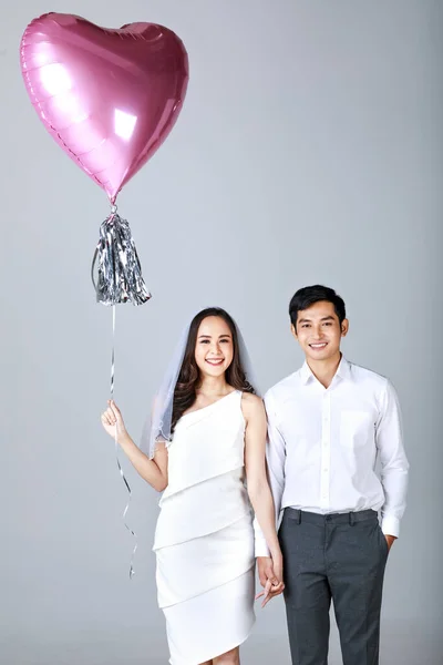 若い魅力的なアジアのカップル 男性は白いシャツを着て 女性は結婚式のベールと白いドレスを着て一緒に手を保持立っている 風船を持ってる女 結婚式前の写真のコンセプト — ストック写真