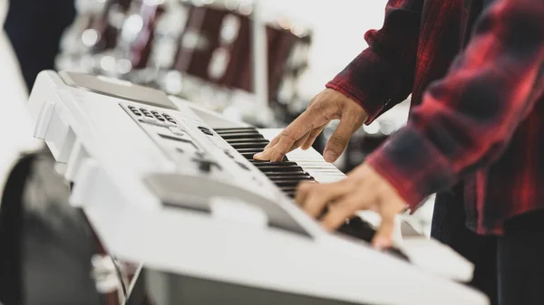 男性音楽家の手のクローズアップショットは 電気キーボードを再生します 背景にドラムで手に選択的な焦点を当てます プロのピアニストが競技会の準備を練習し練習する — ストック写真