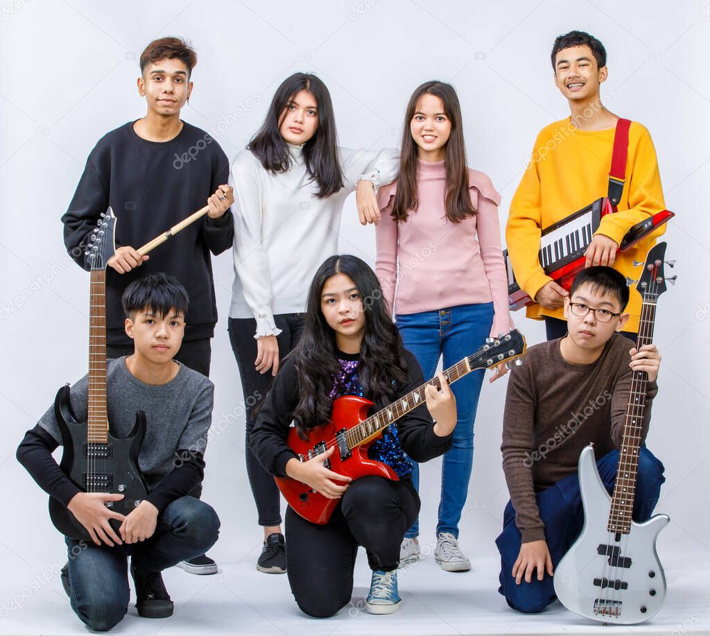 Portrait group shot of seven teenage musicians smiling and looking at camera with white background. Group shot of guitarist, bassist, vocalist, drummer, keyboardist. Concept of musician friends