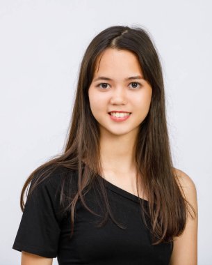 Siyah elbiseli genç Taylandlı bir gencin beyaz arka planda izole edilmiş stüdyoda kameraya bakarken çekilmiş dikey yarı vücut portresi. Balo partisindeki güzel ergen kız.