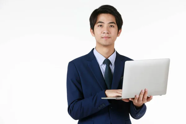 青いスーツの若いアジアのビジネスマン ノートパソコンを手に仕事に立つ 白い背景は正式な感じを与え 空のスペースはテキストを入力できます — ストック写真