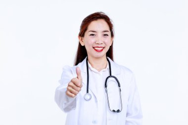 Steteskoplu neşeli genç Asyalı doktor kameraya bakıyor ve beyaz arka plana karşı baş parmağını kaldırıyor..