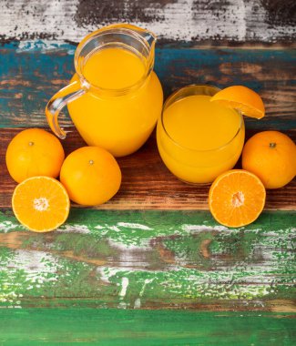 Temiz kavanozda taze portakal suyu ve renkli ahşap masada taze portakalla süsleme. Sağlıklı beslenme için stüdyo resmi konsepti. Stüdyo resmi.