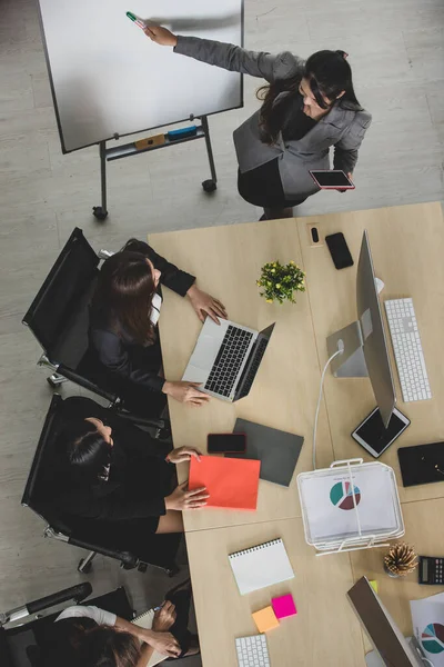 4つの魅力的なアジアの女性のオフィスの同僚のグループの鳥の目のビューは テーブルの上にコンピュータのデスクトップやラップトップとオフィスで一緒に働く正式なビジネススーツで — ストック写真