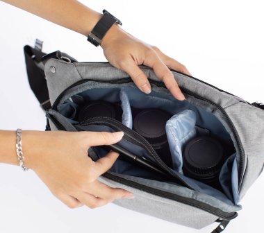 Kadın fotoğrafçıların izole edilmiş yakın çekim stüdyo görüntüleri. Yeni çok amaçlı kumaş kumaş, siyah kamera çantası. Beyaz arka planda, şok geçirmez cep cebinde lens ve tablet var..