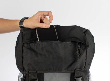 Bir kadının el yapımı, kapalı stüdyo fotoğrafı. Beyaz arka plandaki çantanın cebinden altın rengi akıllı telefon..