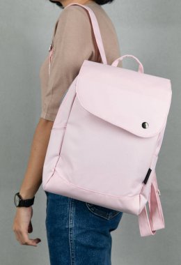 Uzun kollu kahverengi gömlekli ve kot pantolonlu bir kadın modelin, beyaz arka planda büyük, beyaz, çok amaçlı bir çanta asılı halde yakın plan çekimleri..