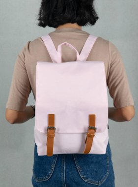 Uzun kollu kahverengi gömlekli ve kot pantolonlu bir kadın modelin, beyaz arka planda büyük, beyaz, çok amaçlı bir çanta asılı halde yakın plan çekimleri..