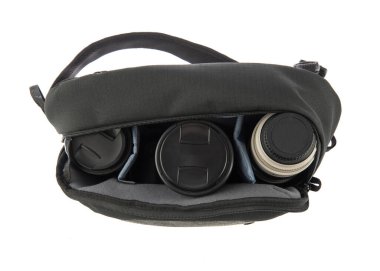 Küçük, siyah ve gri profesyonel fotoğrafçının kapalı çekim stüdyosu şok geçirmez, su geçirmez kumaş, fermuar çanta beyaz arka plandaki yumuşak bölmede flaş ve lens içeriyor..