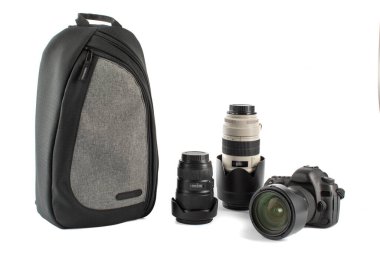 Boyun bantlı, geniş açılı objektifli ve beyaz arka planda şok geçirmez şehir fotoğrafçısı şok geçirmez su geçirmez sırt çantalı büyük siyah DSR kameranın izole edilmiş yakın çekim görüntüleri..