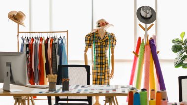 Şapka takan ve ölçü taşıyan mankenler, moda tasarımcıları için parlak giyinme odasında birçok renkli elbise ve iplik bulunan kostüm..