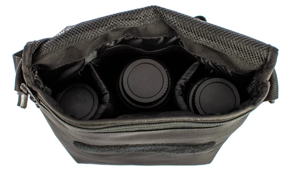 Ayrı bir yakın çekim stüdyo çekimi. Yeni, günlük, çalışan fotoğraf makinesi, çapraz vücut çantası, kompartıman cepleri ve fotoğrafçı için cırt cırtlı kayış, beyaz arka plan önünde üç lens..