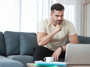 Düşünceli, ciddi bir Kafkasyalı işadamı evde dizüstü bilgisayarla çalışıyor. İş sorunları çözmek ve iş ilhamı kavramı bulmak