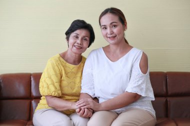 Asyalı orta yaşlı kadın büyük annesine sevgi ve özenle sarılıyor..