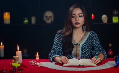 Genç ve sevimli Asyalı kadın falcı çingene tarzı giysiler içinde gözlerini kapatıp loş odada fal bakarken.