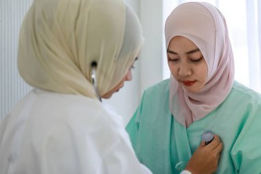 Genç kadın müslüman doktor hastanede steteskopla Müslüman hastanın kalbini kontrol ediyor..