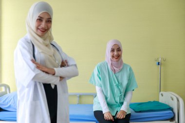 Genç Müslüman kadın doktor ve kameraya poz veren Müslüman hastanın portresi..