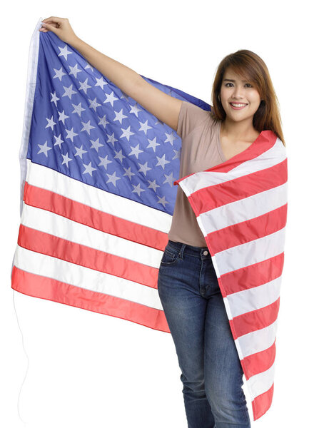 Isolated portrait shot of beautiful young Asian girl stand holding showing large United States of America national flag in front white background represent celebration on 4th of July independence day.