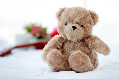 Kahverengi tüylü oyuncak ayı, gitarın yanında oturmuş keyifli bir bayramda çalan müzikten zevk alan sevimli bir oyuncak gibi.