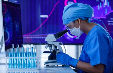 Koruyucu hijyen maskesi takan araştırmacı ya da bilim adamı laboratuarda mikroskop ve test tüpleri üzerinde çalışıyor..