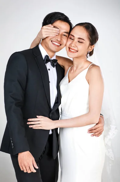 若い魅力的なアジアのカップル 花嫁と新郎 女性は白いウェディングドレスを着て 黒いタキシードを着た男が互いをからかっている 結婚式前の写真のコンセプト — ストック写真
