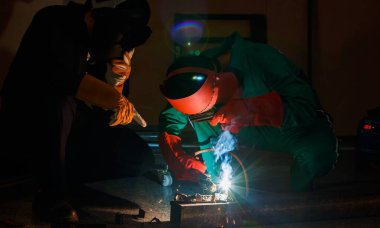 Tamirciler geceleri fabrikada fazla mesai yapmazlar. Tamirci tulumları, eldivenleri, botları ve metal kaynaklama kaskları olan güvenlik kıyafetleri giyen mühendisler..