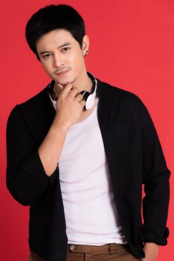 Asyalı erkekler düşünmeyi, ellerini yanlarının altına koymayı ve dirseklerini şüpheli bir konsepte sokmayı göze alırlar. Kırmızı arka plan. stüdyoda